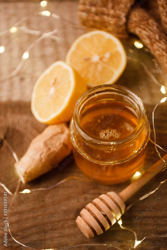 Composition with honey, lemon, ginger root as natural cold remedies on wooden background, winter holiday cozy home concept Composition with honey, lemon, ginger root as natural cold remedies on wooden background, winter holiday cozy home concept