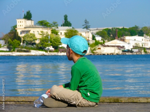 the child sits on the shore and looks into the distance