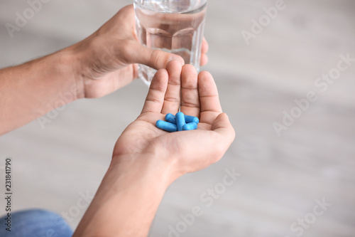 Man holding pills and glass of water, closeup