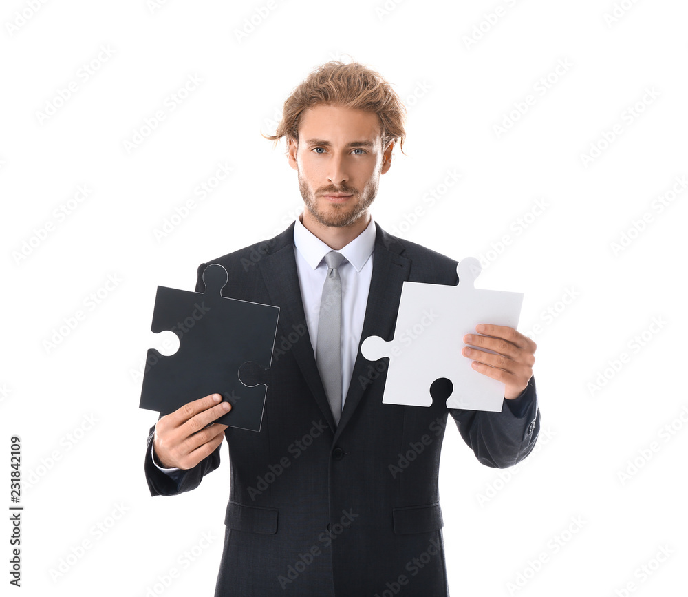Young businessman with pieces of jigsaw puzzle on white background Young businessman with pieces of jigsaw puzzle on white background