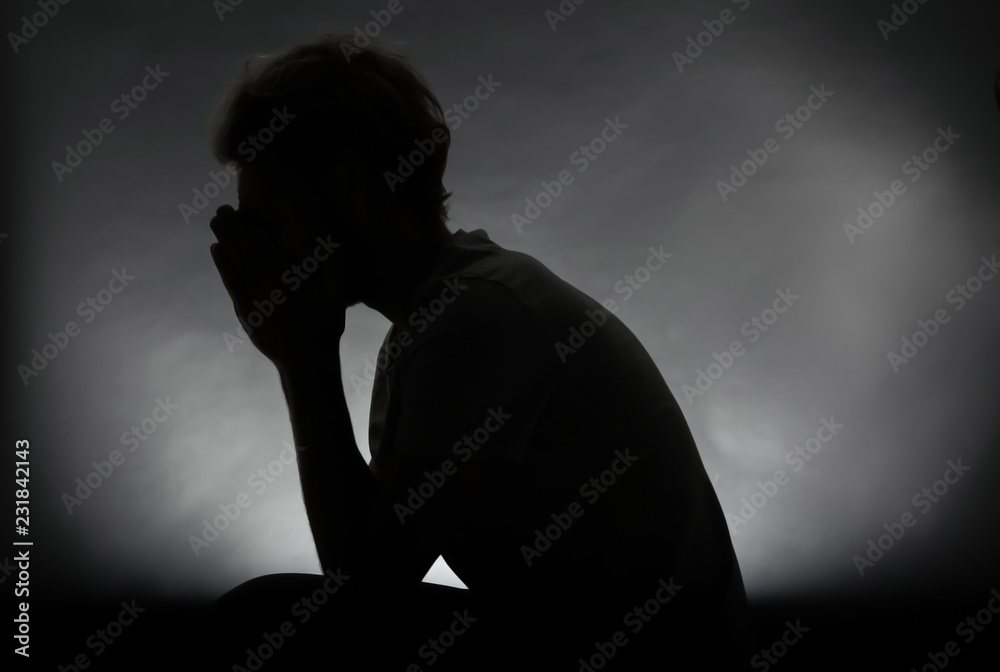 Silhouette of stressed man on dark background