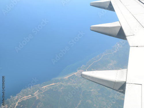 Beautiful view of earth and sea under the wing of plane. Costal view from above. Travel concept. Freedom concept.