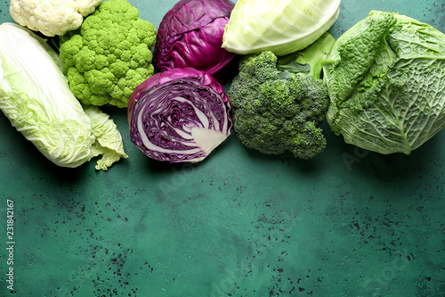 Different kinds of cabbage on color background