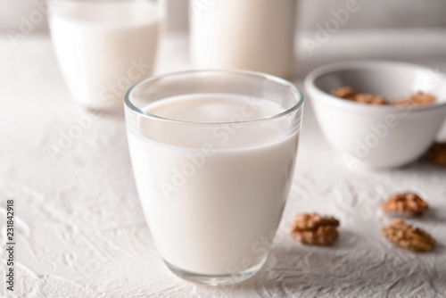 Glass of tasty milk on white table