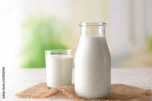 Valokuva Bottle and glass of tasty milk on light table