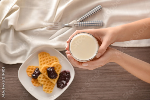 Woman holding glass of tasty milk over table  top view
