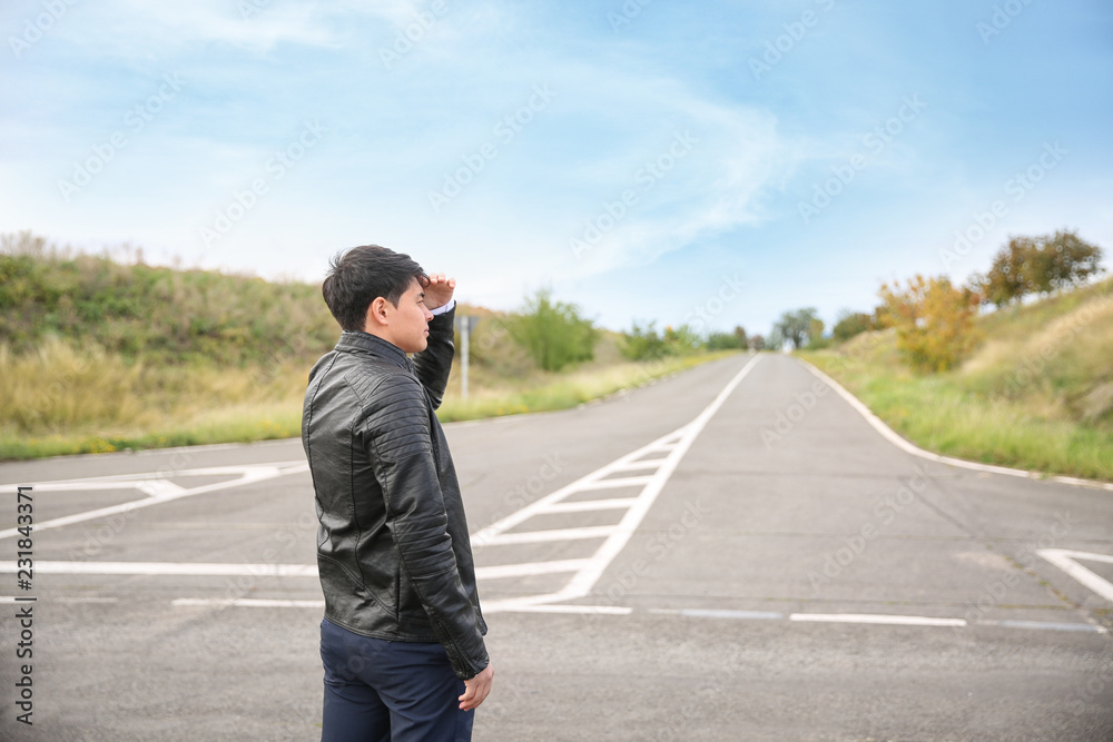 Young man standing at crossroads. Concept of choice