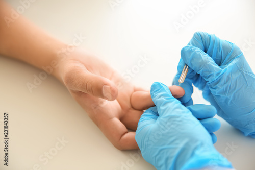 Doctor using lancet to get blood sample for test, closeup