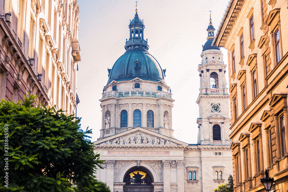 The facade and dome of the Basilica of St. Stephen in Budapest, between two buildings. View from afar. The main basilica for Catholics of Hungary. The largest church in the country