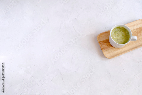 Matcha latte in white cup on wooden tray