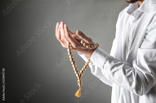 Young Muslim man with rosary beads praying on dark background photo
