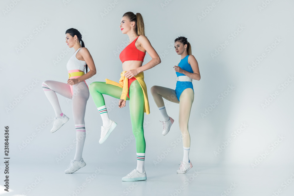 Obraz premium low angle view of sporty young women exercising together on grey