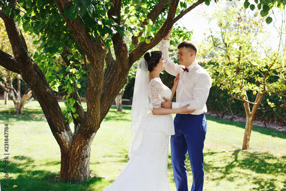 Just married loving hipster couple in wedding dress and suit in the park. Happy bride and groom walking in the beautiful garden. Romantic Married young family. Just married loving hipster couple in wedding dress and suit in the park. Happy bride and groom walking in the beautiful garden. Romantic Married young family.