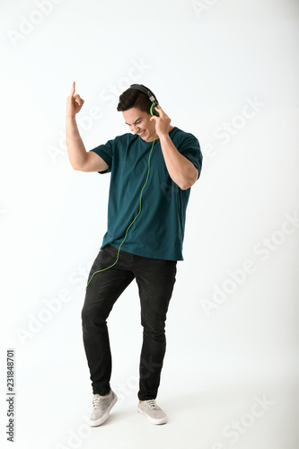 Emotional young man listening to music on white background