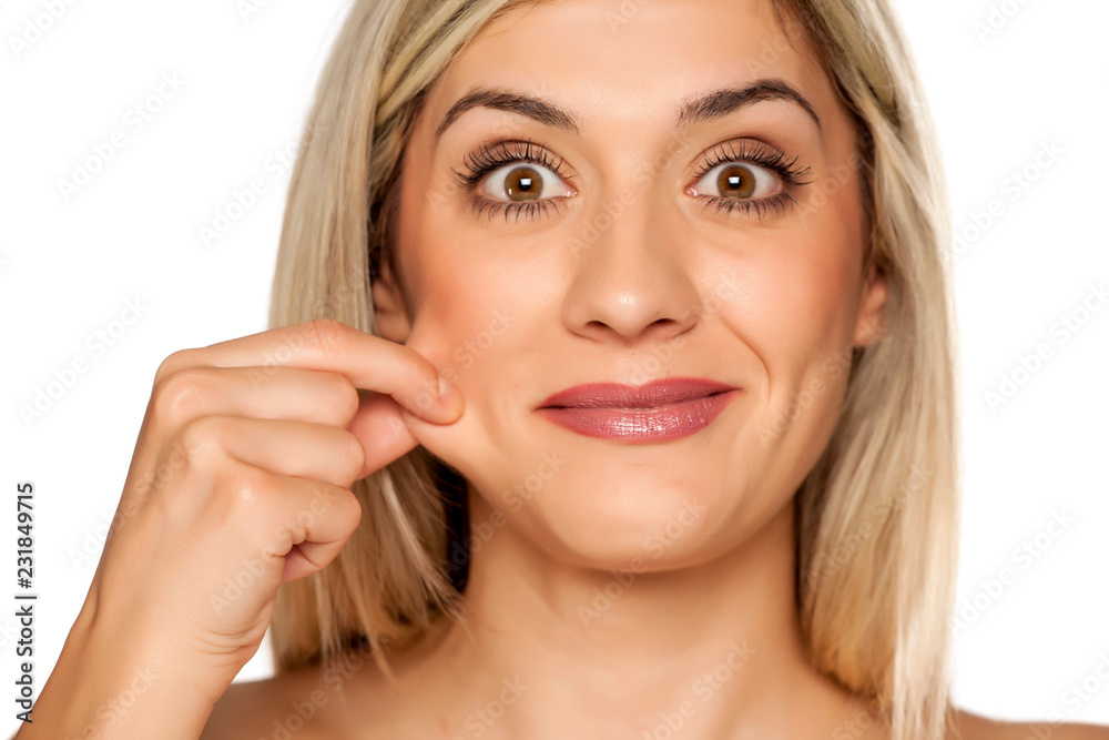 Portrait of young blond woman, pulling her cheek on white background Portrait of young blond woman, pulling her cheek on white background