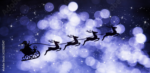 A sleigh with Santa Claus pulled by four reindeers against the background of a starry and illuminated night sky