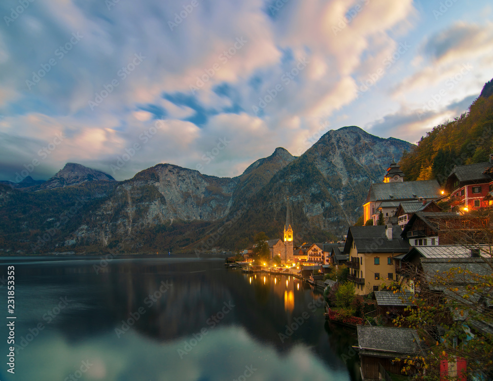 Scenic view of famous Hallstatt mountain village in the Alps under picturesque moving clouds after sunset, Austria