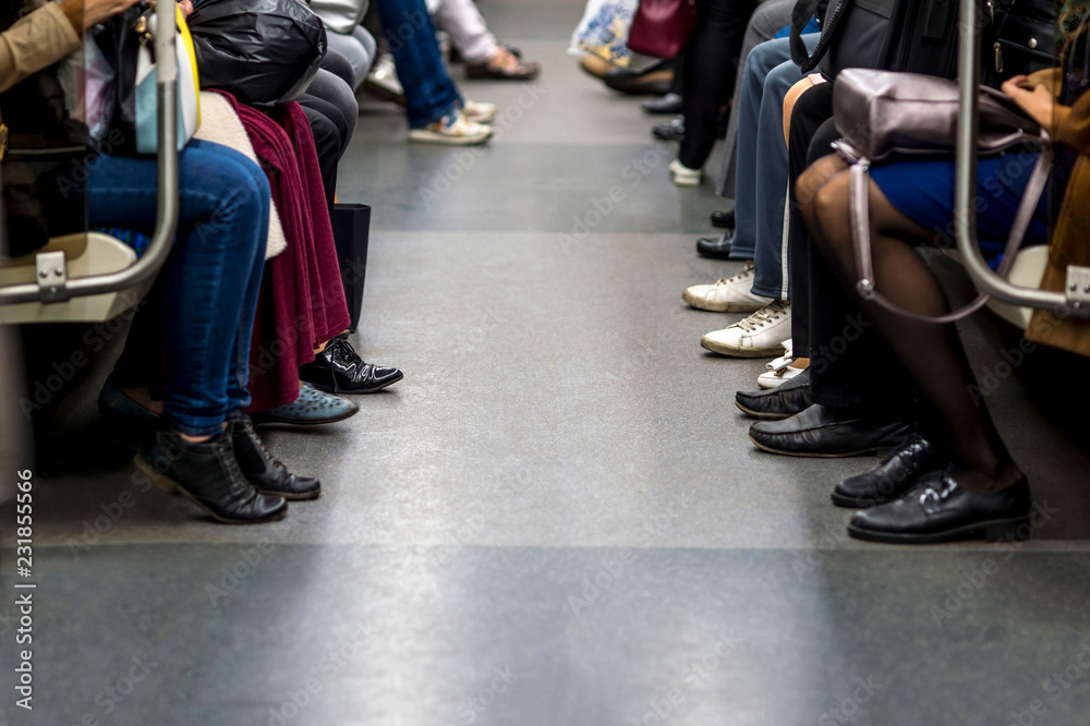 Fototapeta premium Feet of people sitting opposite each other in a subway car. The concept of spending life time waiting