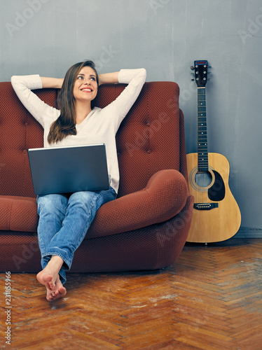 Casual dressed woman sitting on sofa with laptop.