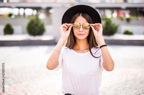 Fashion portrait pretty young woman wearing a black hat sunglasses on street background © dianagrytsku