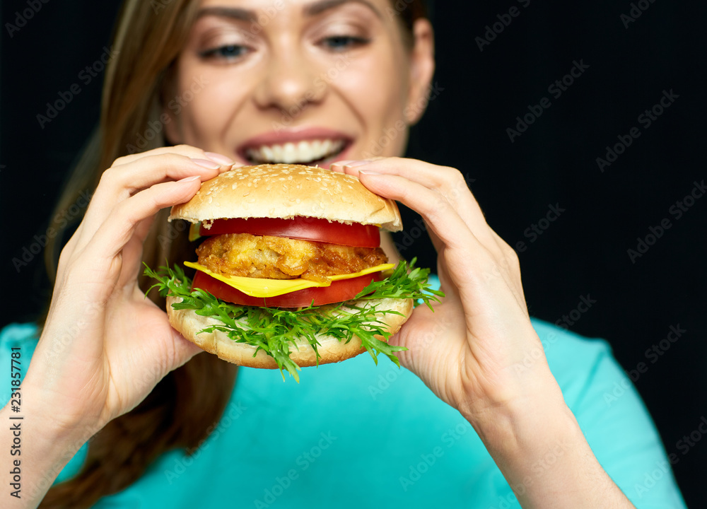 Woman eating cheeseburger, isolated portrait