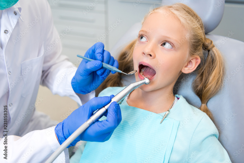 cropped shot of dentist examining teeth of beautiful little child cropped shot of dentist examining teeth of beautiful little child