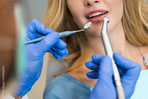 cropped shot of dentist examining teeth of female client