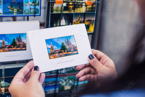 Tourist holds a postcard with a picture of a popular place in Budapest. This is a good souvenir after the trip. Fisherman's Bastion is a very visited historical place in Budapest