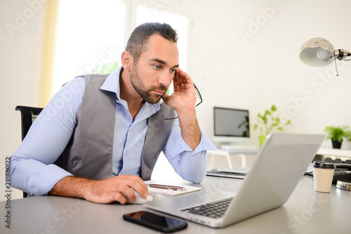 portrait of handsome trendy casual mid age business man in office desk with laptop computer