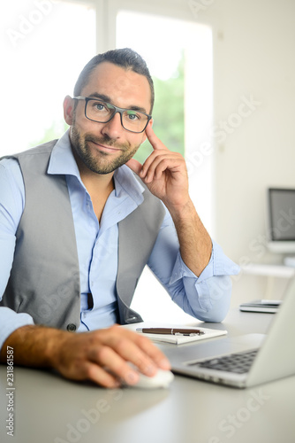 portrait of handsome trendy casual mid age business man in office desk with laptop computer