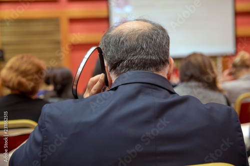 Unrecognizable business people using headphones for translation during event . bald security guard with the headset to control people . heated debate at a conference discussion