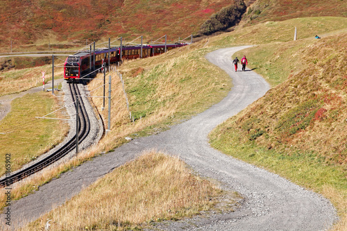 Tourists heading for Fallbodensee (Fallboden lake) with passing by train heading for the Top of Europe - Jungfraujoch; Fallboden, Jungfrau Region, Switzerland photo