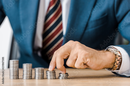 male hand counting silver coins at wooden table