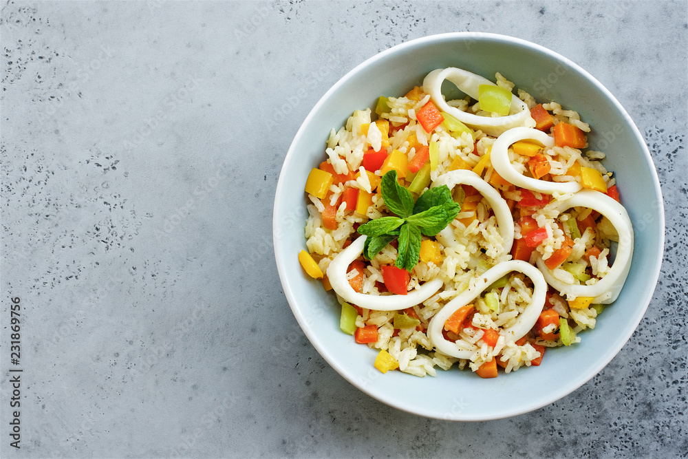 Rice with vegetables and squid rings. Top view, gray concrete background Rice with vegetables and squid rings. Top view, gray concrete background