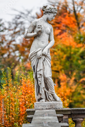Statue of sensual naked Roman renaissance era woman with flowers at golden Autumn, Potsdam, Germany, details, closeup