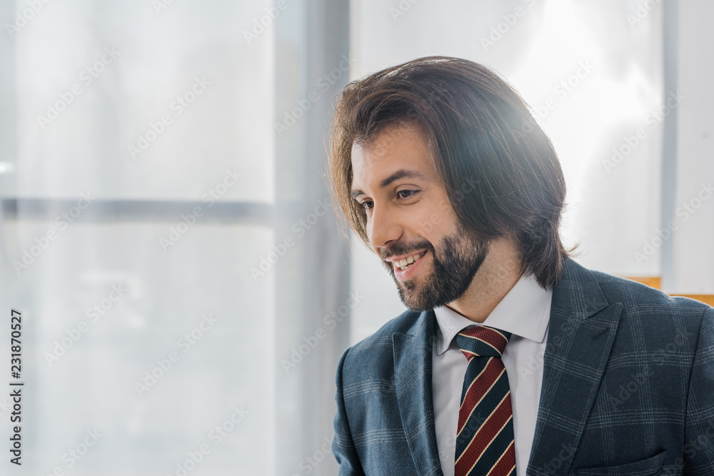 young smiling businessman in suit standing in office