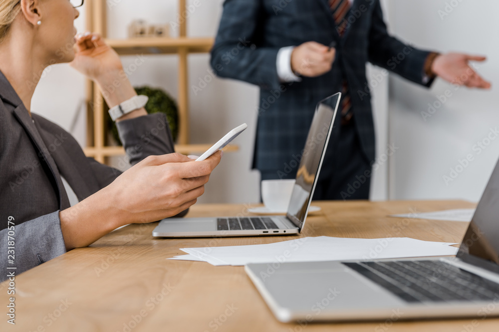 young businesswoman holding smartphone at table in office young businesswoman holding smartphone at table in office