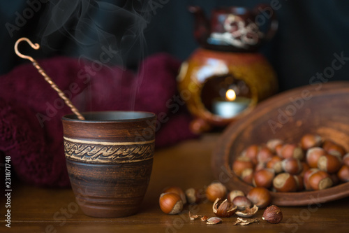 Dark background with a hot drink in a ceramic Cup and the scattered nuts hazelnuts on a wooden surface.