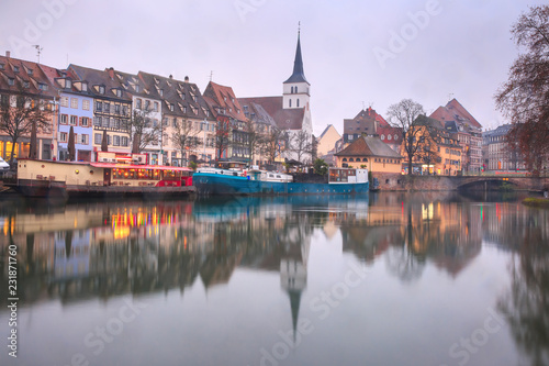 Picturesque quai des Pecheurs, Fisherman Wharf, and Protestant church of Saint Guillaume with mirror reflections in the river Ile during morning blue hour, Strasbourg, Alsace, France