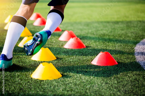 Soccer player Jogging and jump between cone markers on green artificial turf for soccer training.