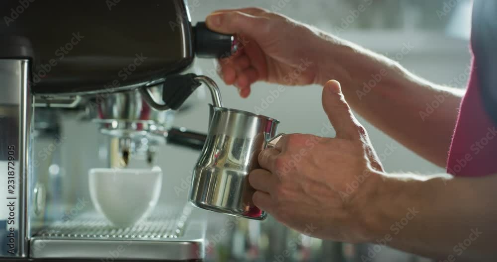 Macro of a barman while he is preparing the milk for cappuccino by using the coffee machine, in a bar. Macro of a barman while he is preparing the milk for cappuccino by using the coffee machine, in a bar.