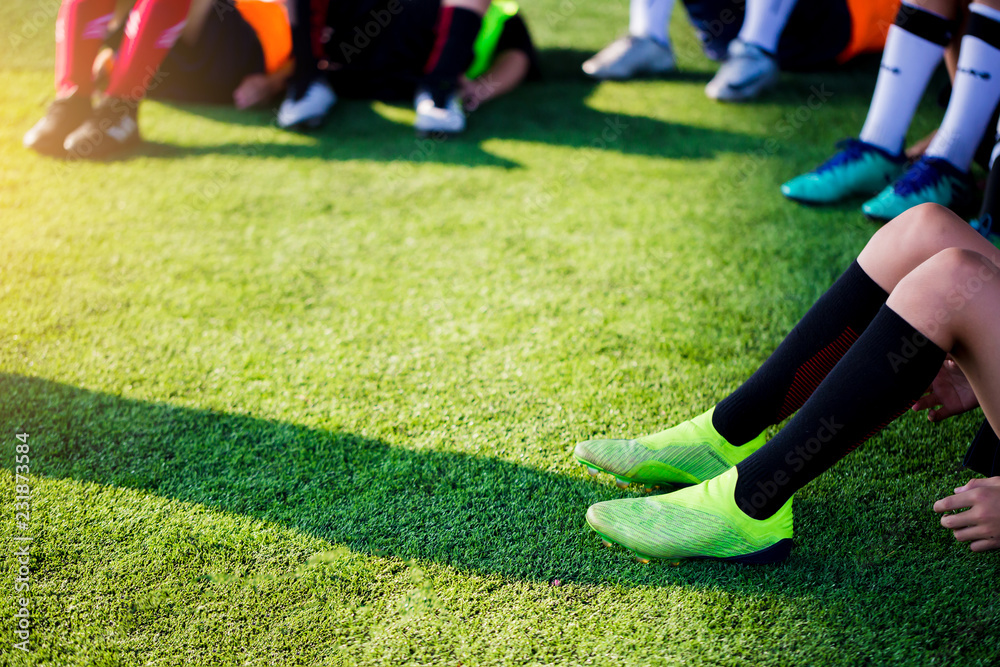 Kid soccer players are sitting with warming on green artificial turf for stretch muscles before and after play soccer game. Kid soccer players are sitting with warming on green artificial turf for stretch muscles before and after play soccer game.