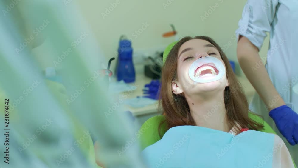 Woman patient at teeth whitening procedure in dental clinic. Dentist