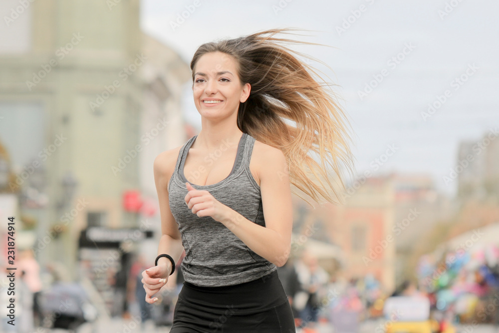 Smiling girl running on city street.