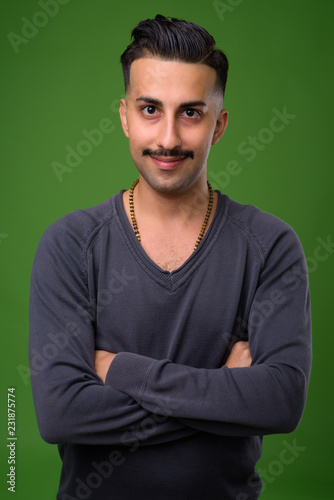 Young handsome Iranian man with mustache against green backgroun © Ranta Images