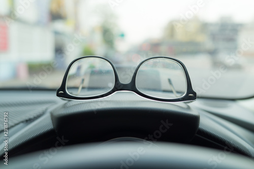 Eyewear placed on the car console, Is a view inside the car of the driver on blurred traffic background,