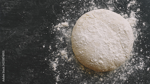 Raw yeast dough for pizza, bread or pasta. Dark food background. Copy space for text