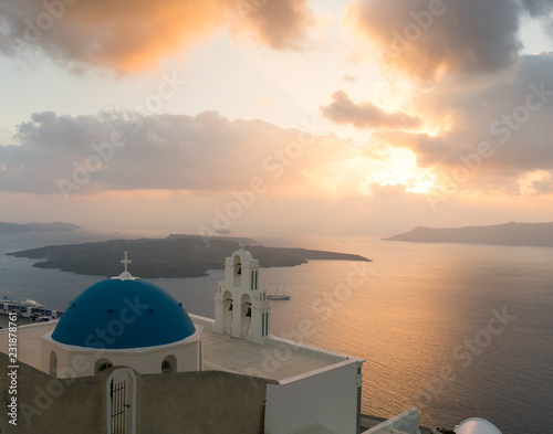 sunset over aegean sea with view to Virgin Mary Catholic Church Three Bells of Fira, Santorini.
