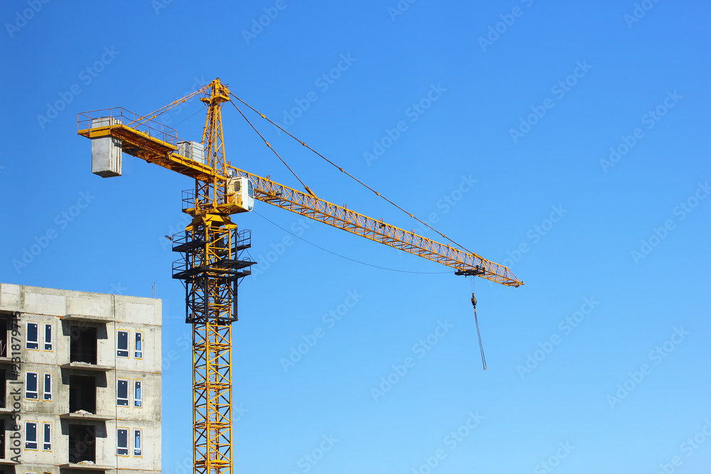 tower crane in motion on the background of the object under construction and the blue sky tower crane in motion on the background of the object under construction and the blue sky