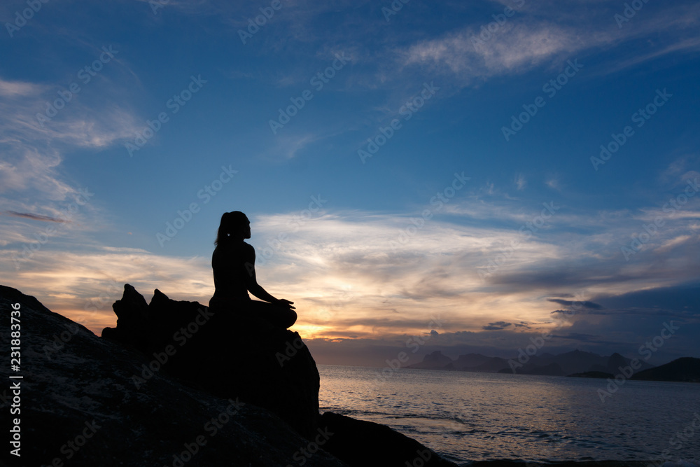 mulher meditando na praia, no pôr do sol